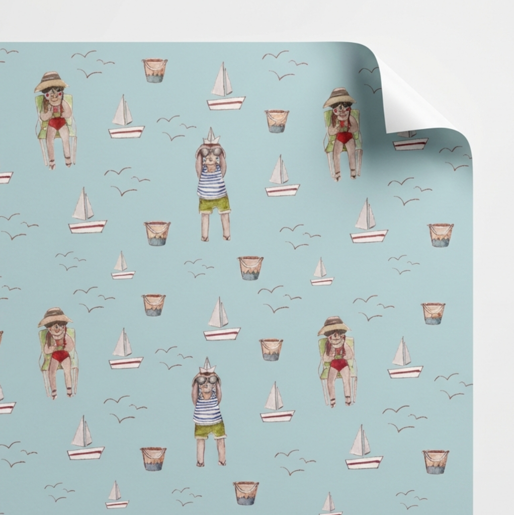 Roll of paper with beach-themed pattern featuring people, sailboats, and seagulls on a light blue background.
