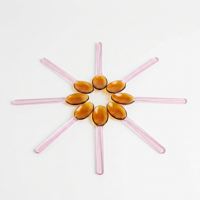 
                    
                      Pink and Amber Borosilicate Stirring Spoons, multiple arranged in a circular flower pattern, top view.
                    
                  