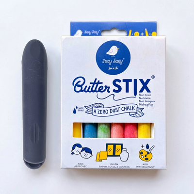 
                    
                      Jaq Jaq Bird Butterstix 12-piece dustless chalk set, assorted rainbow colors, with dark gray holder, flat lay.
                    
                  