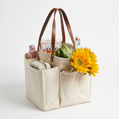 
                    
                      Multi-Pocket Canvas Market Tote, natural cotton canvas with brown vegan leather straps, filled with groceries and…
                    
                  