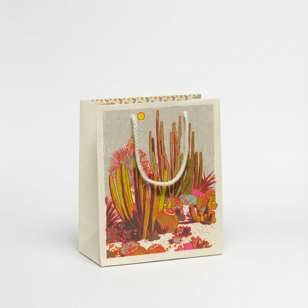 Red Cap Cards Cactus Scene gift bag, red, green, yellow, pink cactus design on light paper, white rope handles, front view.