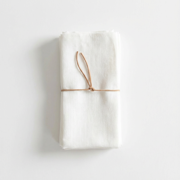 Celina Mancurti Heirloom Linen Napkins, set of 4, natural off-white 100% linen, tied with brown leather cord, flat lay.