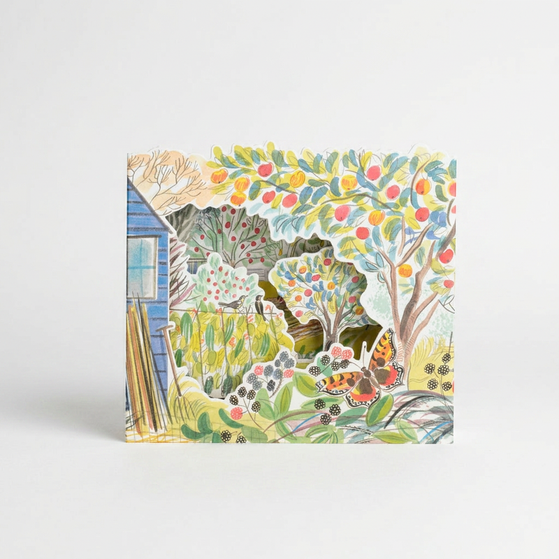Art Angels Orchard Allotment die-cut card by Emily Sutton, layered garden scene with blue shed, fruit trees, butterfly on…