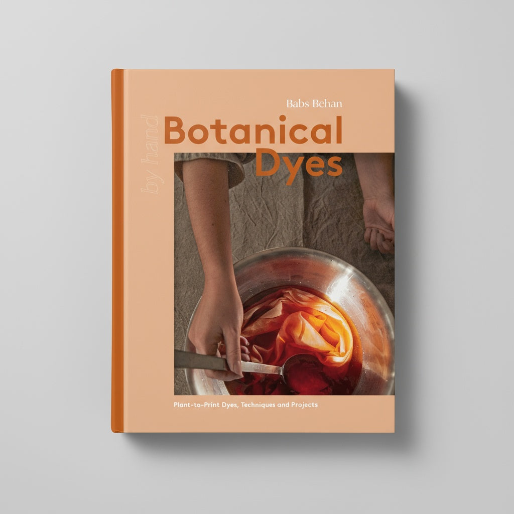 Chronicle Books Botanical Dyes book, peach cover with hand stirring fabric in dye, orange spine, front view on white.