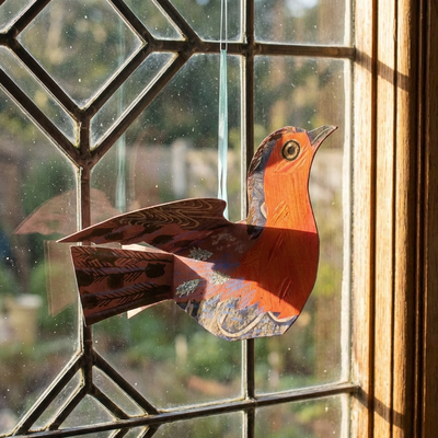 
                    
                      Flying Robin Die-Cut Card by Mark Hearld, red and blue illustrated cardstock, hanging by ribbon in leaded window, sunlit…
                    
                  