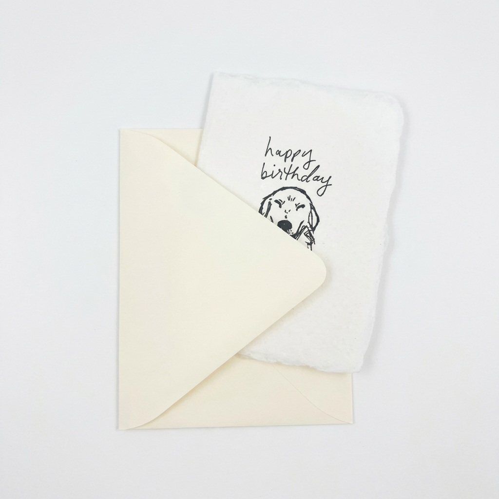 Letterpress greeting card with 'happy birthday' text and a dog illustration on a white background