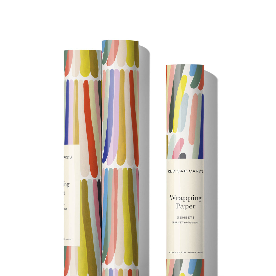 Three Rainbow Stripes wrapping paper rolls, multi-color organic brushstroke-like stripes, Red Cap Cards label visible,…