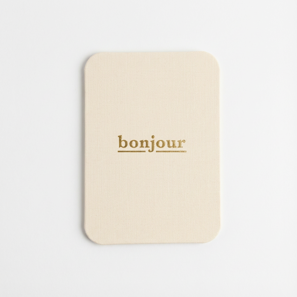 'bonjour' Cloth-Covered Postcard, cream cotton cloth covering, gold foil 'bonjour' text, full front view.