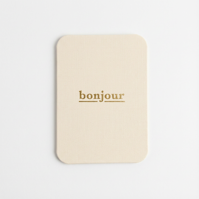 
                    
                      'bonjour' Cloth-Covered Postcard, cream cotton cloth covering, gold foil 'bonjour' text, full front view.
                    
                  