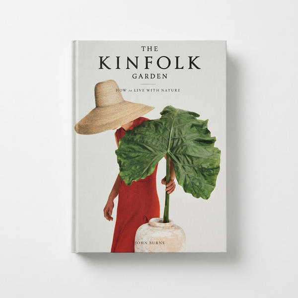 Hachette Book Group, The Kinfolk Garden hardcover book, cover showing person in straw hat, red dress, holding large green…