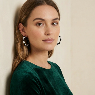 
                    
                      Sol hoop earrings, black and white tortoise acetate pattern, on model's ear close-up.
                    
                  