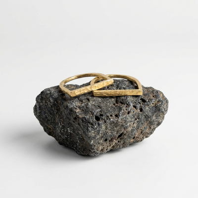 
                    
                      Brass ring on a textured black stone with a white background
                    
                  