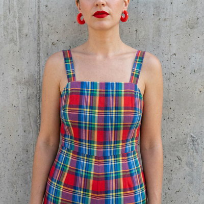 
                    
                      Mali Cherry Red acetate hoop earrings worn on model's ear, with a colorful plaid outfit, against a concrete wall.
                    
                  