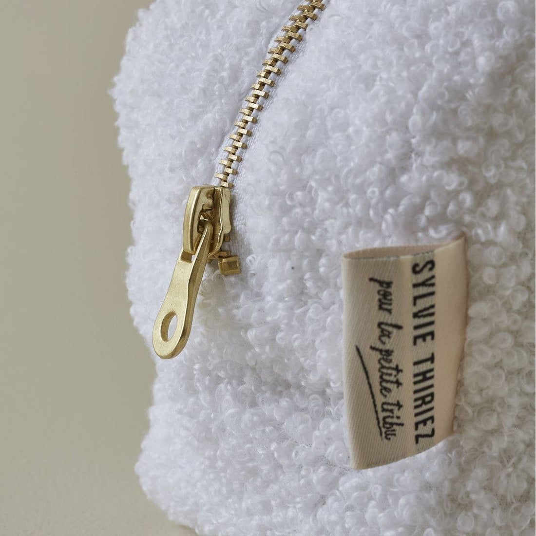 Sylvie Thiriez Petit Coeur toiletry bag, white terry cloth close-up of gold-toned zipper and brand tag.