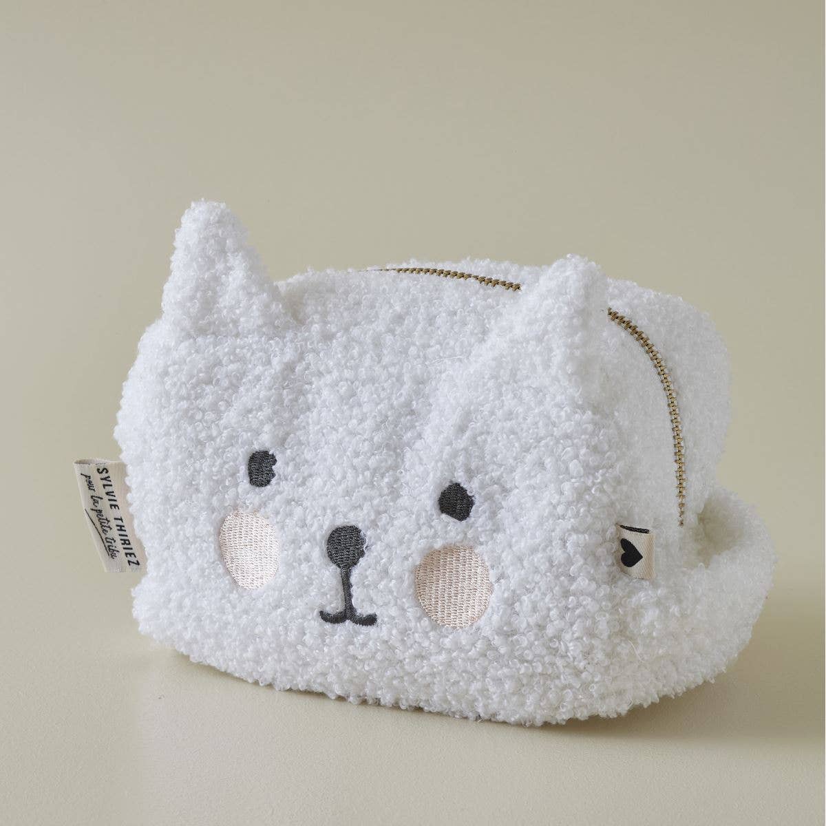 White fluffy pouch with a cat face design on a beige background