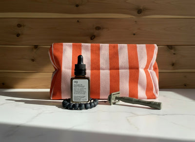 
                    
                      Vic Toiletry Bag, Tomato + Candy Pink striped cotton canvas, angled view with avocado oil, black beaded bracelet, and razor…
                    
                  