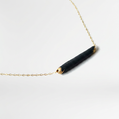 
                    
                      Bar necklace, matte black porcelain pendant with gold-dipped ends, 14k gold-filled chain, angled close-up.
                    
                  