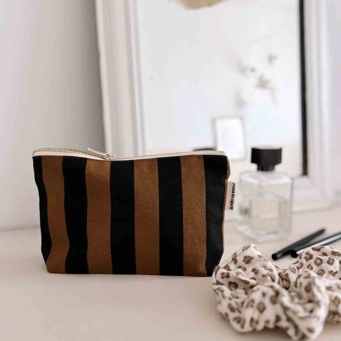Sofia Pouch toiletry bag, cumin and black striped cotton canvas, with visible gold-tone zipper pull, angled front view.