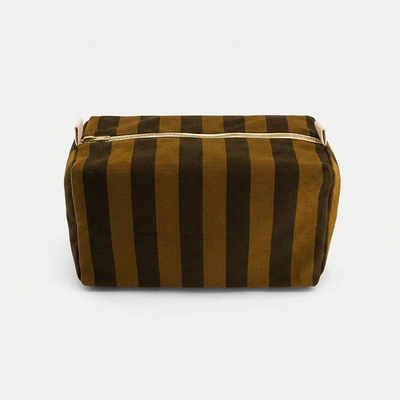 
                    
                      Rose in April Vic Toiletry Bag - Cumin + Black Stripe studio product photo hanging from a wooden wall hook on a neutral…
                    
                  