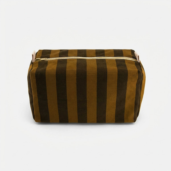 Rose in April Vic Toiletry Bag - Cumin + Black Stripe studio product photo hanging from a wooden wall hook on a neutral…