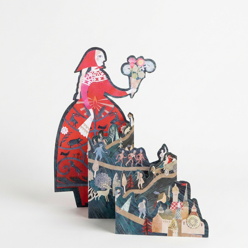 Art Angels Storyteller die-cut stationery card, multi-color illustration of woman in red with layered landscape, front view…