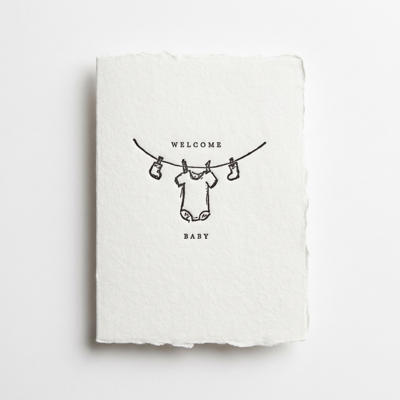 Farmette "Welcome Baby" greeting card, handmade paper with black line drawing of baby clothes on a clothesline, front view…