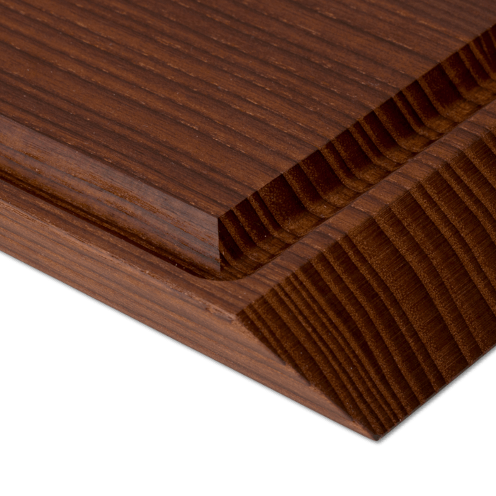 Rå wood cutting board, close-up of dark heat-treated ash wood grain with rounded juice groove and ridged edge detail.