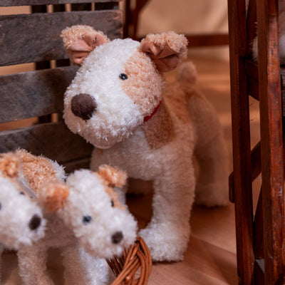 
                    
                      Eliot stuffed animal, white and light brown plush with red collar, standing behind two others in a wicker basket.
                    
                  