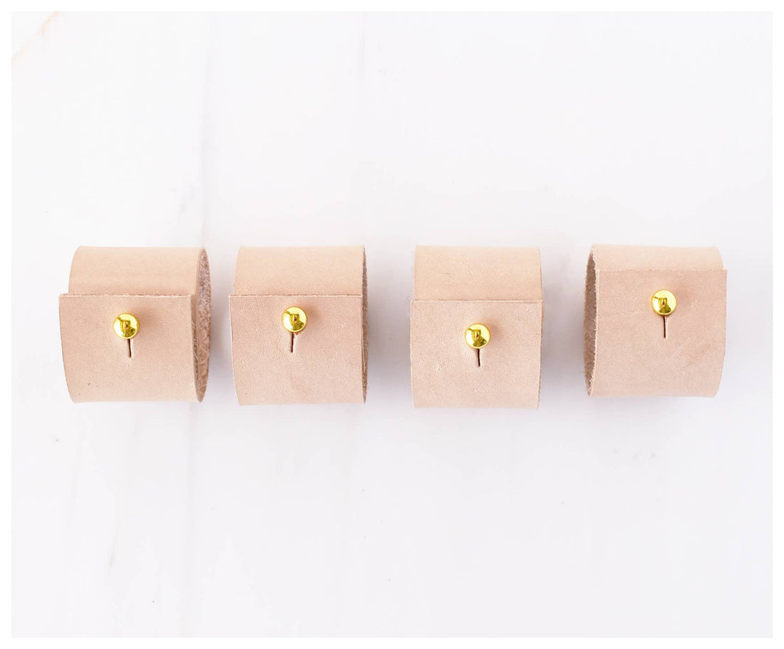 Tan Leather Napkin Rings set of 4, each with a brass clip fastener, lined up showing top-down detail.