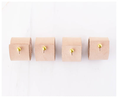 
                    
                      Tan Leather Napkin Rings set of 4, each with a brass clip fastener, lined up showing top-down detail.
                    
                  