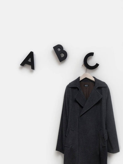 
                    
                      Black solid beech wood Alphabet Wall Hooks - ABC, letter C holding a dark coat on a hanger, on white wall.
                    
                  
