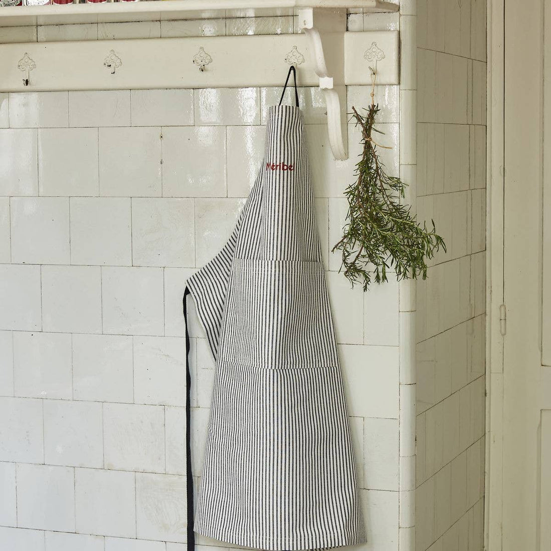 Sylvie Thiriez French Striped Cotton Apron, black and white vertical stripes, red 'Merbe' embroidery, hanging front view.