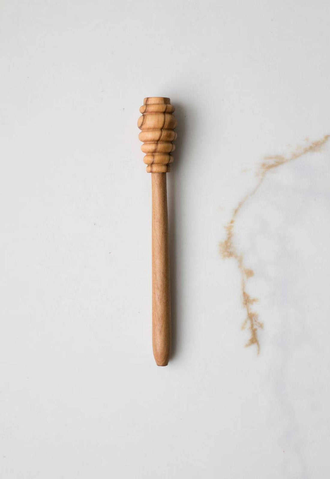 Olive Wood Honey Dipper, light brown olive wood grain, flat lay showing grooved head and smooth handle.