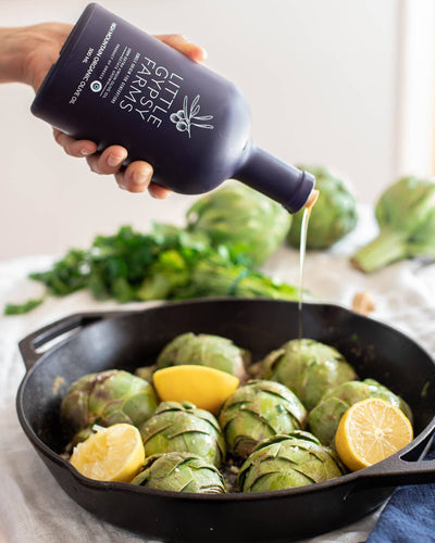 
                    
                      Little Gypsy Farms High Mountain Organic olive oil, dark blue bottle pouring into a cast iron pan with artichokes and fresh…
                    
                  
