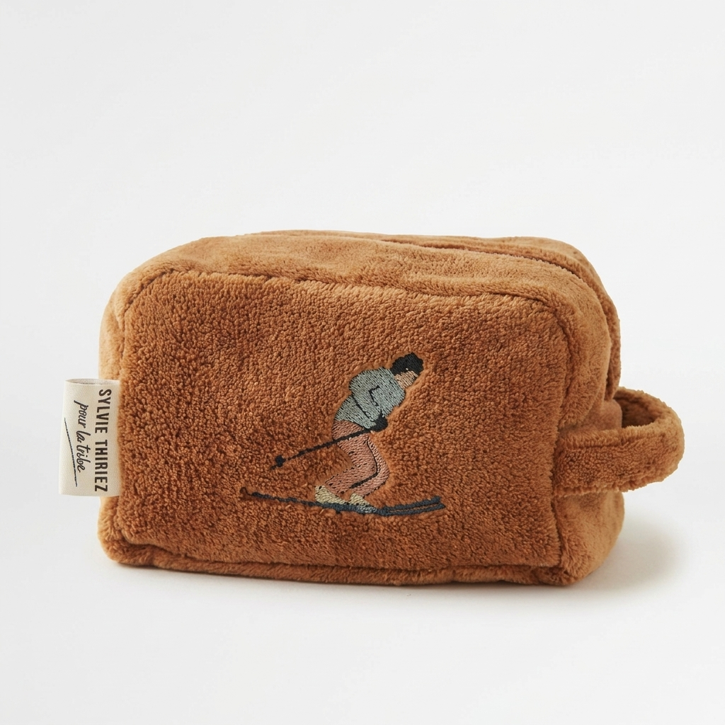 Sylvie Thiriez Après-Ski children's toiletry case, brown velvet fleece with embroidered skier, front view on white.
