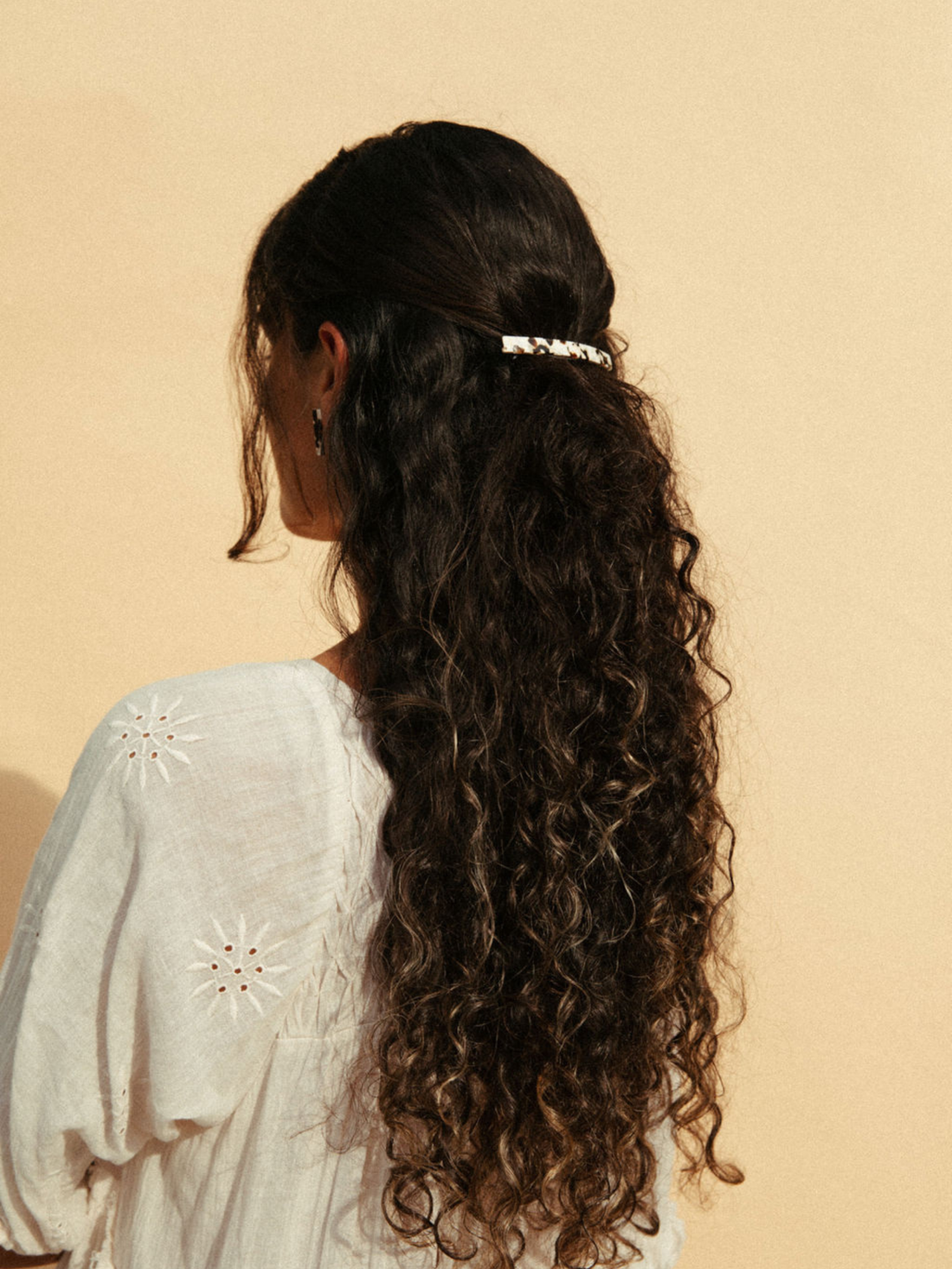 Coco Cream hair clip, cream speckled cellulose acetate, worn on long dark curly hair, back view
