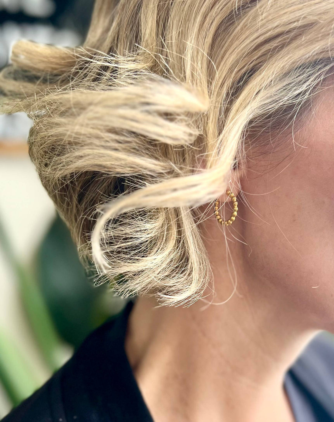 Gold-plated Beaded Hoop earrings, close-up view on ear, nestled within styled blonde hair.