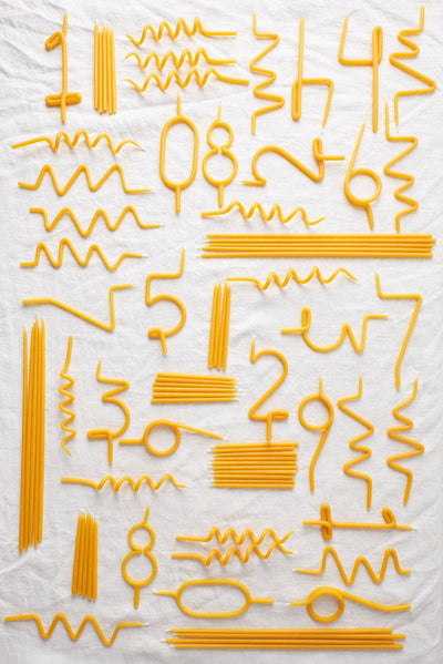 
                    
                      Collection of yellow Twirl Beeswax Birthday Candles, featuring number, wavy, and straight shapes, flat lay on white.
                    
                  