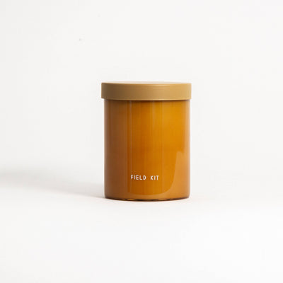 
                    
                      Field Kit The Beekeeper Glass Candle, Honey + Clover variant, with amber wax and matte tan lid, front view on white.
                    
                  