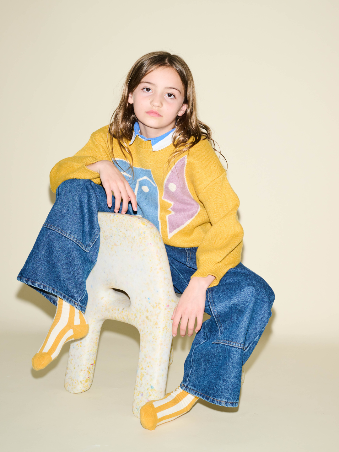 Kids Stripe Sock, yellow and white stripes, worn on a child's feet under wide-leg blue jeans.