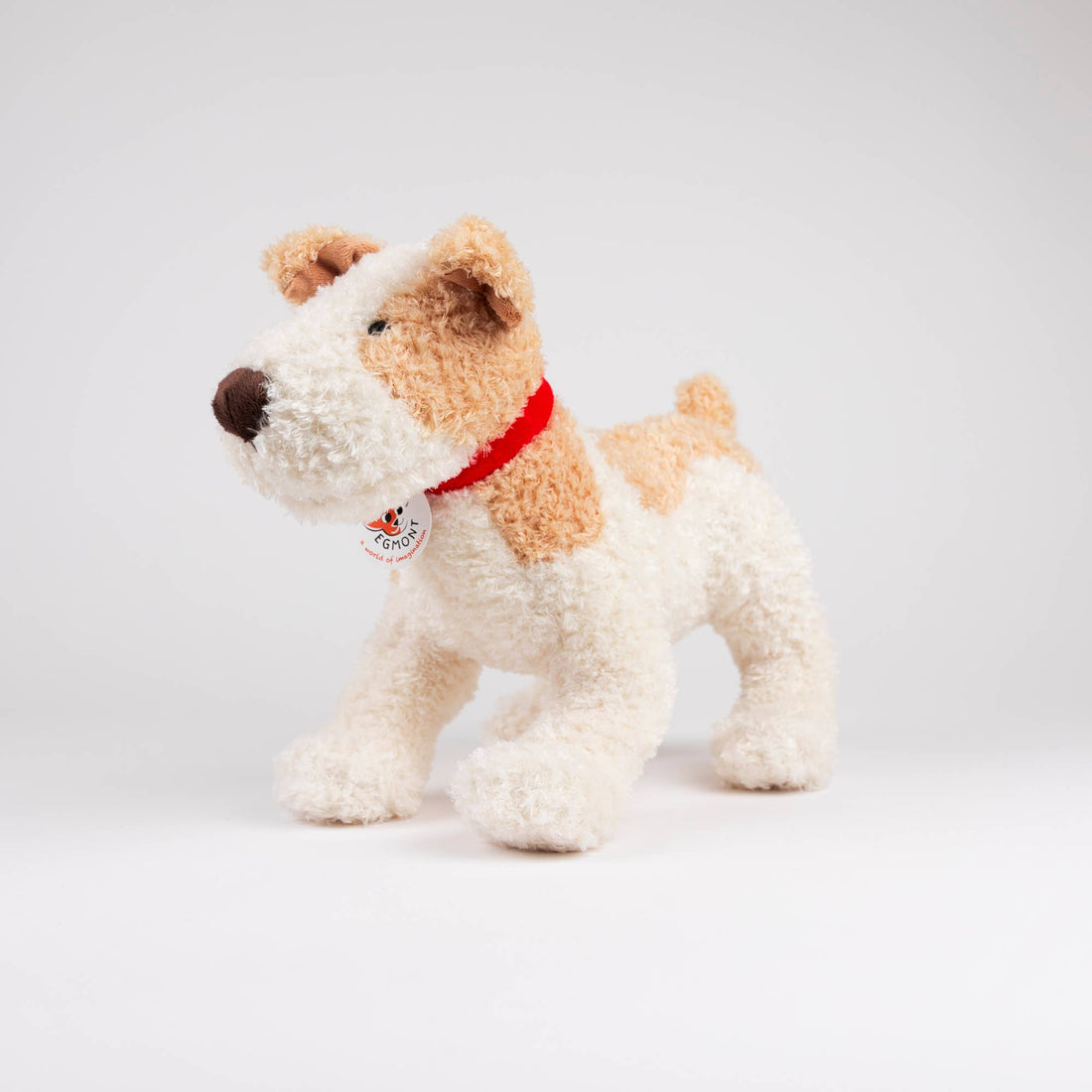Eliot plush stuffed dog, white and tan textured polyester, red fabric collar with visible Egmont tag, standing angled view.