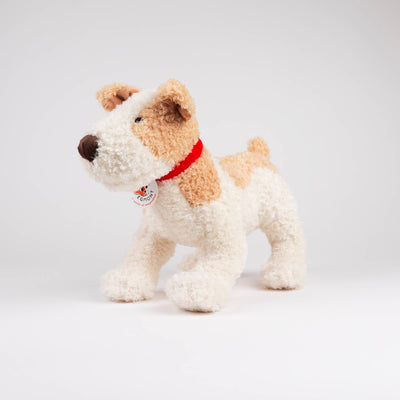 
                    
                      Eliot plush stuffed dog, white and tan textured polyester, red fabric collar with visible Egmont tag, standing angled view.
                    
                  