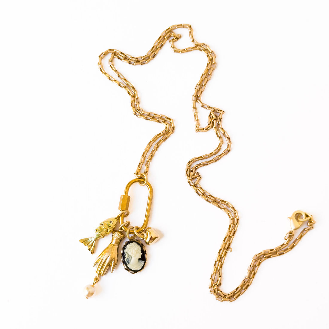 Gold Carabiner Charm Necklace, 24K satin gold-plated chain flat lay with fish, hand, cameo, heart, and pearl charms.