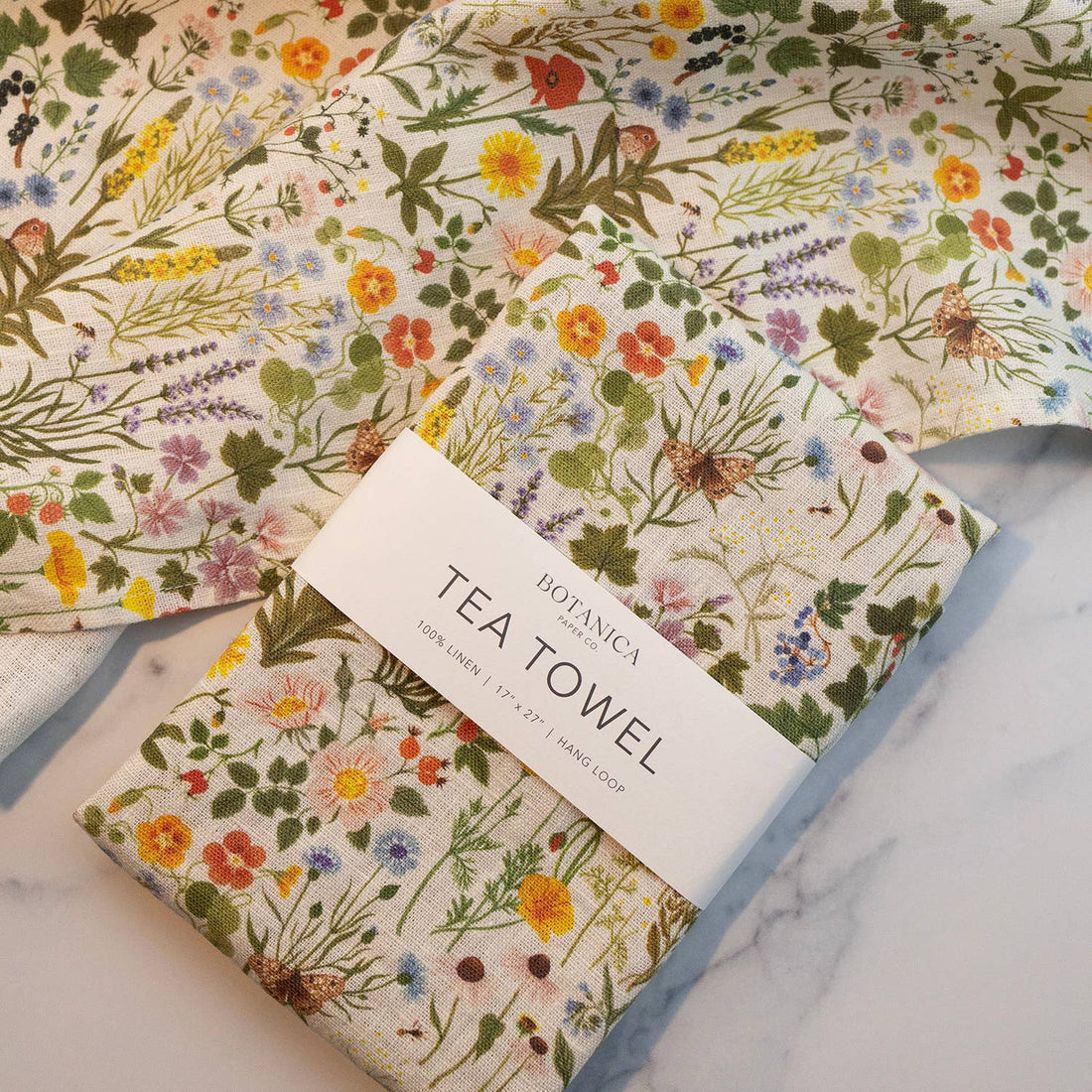 Botanica Paper Co. Botanist 100% linen tea towel, folded with branded band, vibrant multicolor wildflower pattern.