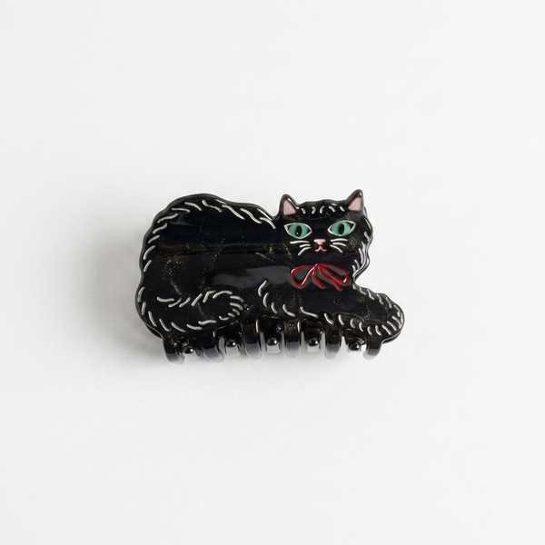 Winona Irene Black Kitty hair clip, black glittery acetate with green eyes and red bow, front view on white.