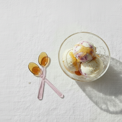 
                    
                      Pink and Amber Borosilicate Stirring Spoons, pair crossed flat lay on white cloth, shown with ice cream for scale.
                    
                  
