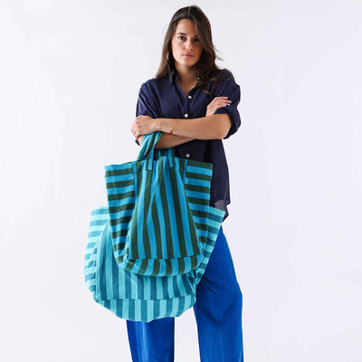 
                    
                      Elisabeth Tote Bag, 100% cotton with vertical turquoise and olive stripes, held by model, with a second lighter striped tote…
                    
                  