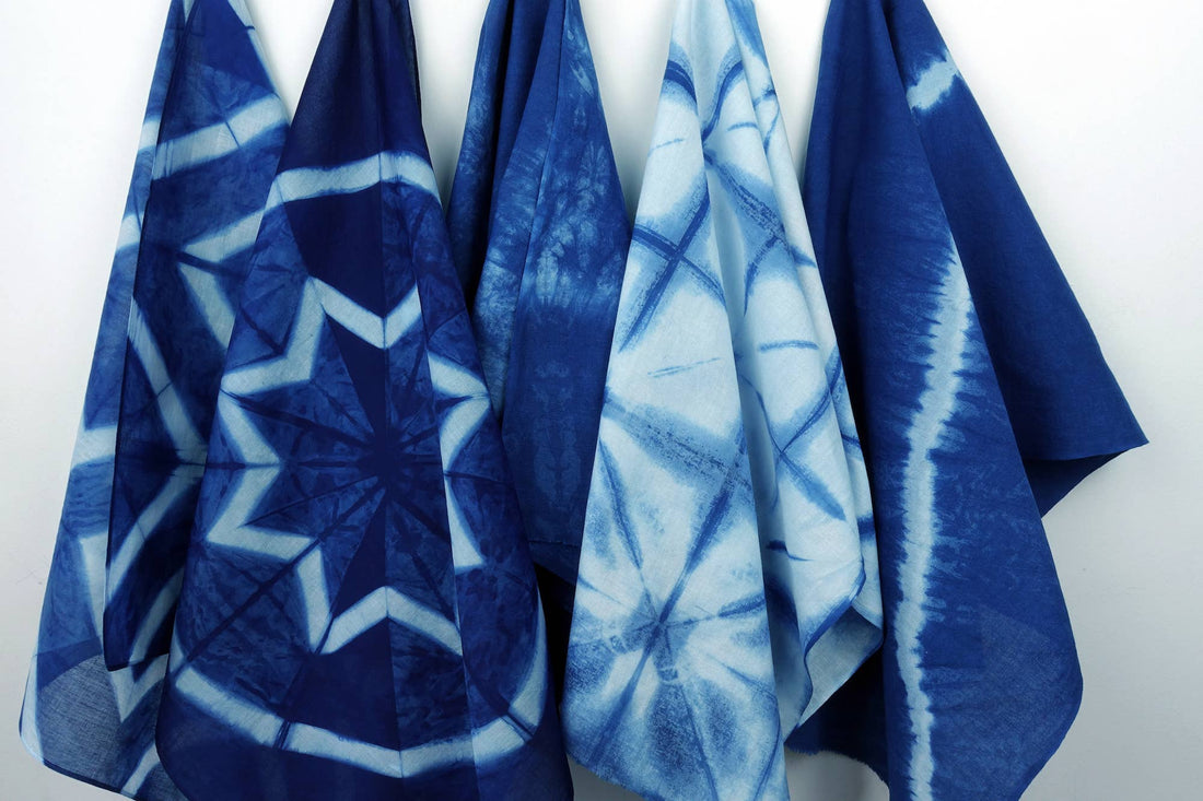 Yamato Indigo Shibori Kit finished textiles: four draped cotton pieces, each with unique indigo tie-dye shibori patterns.