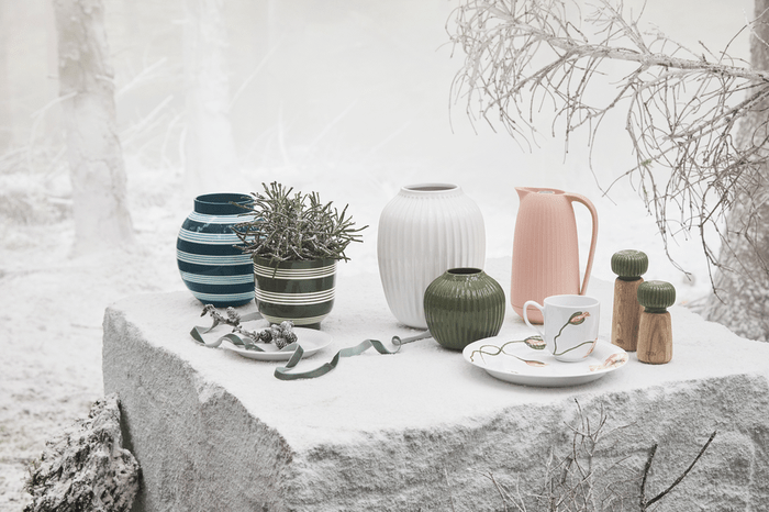 Hammershøi oak and dark ceramic spice grinders, a pair set on snow-covered stone in winter scene.
