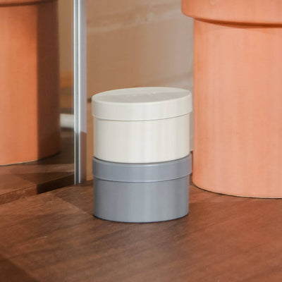 
                    
                      The Librarian tin candles, light cream and grey, stacked on a dark wood surface. Angled, close-up view.
                    
                  